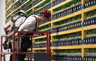 An aerial view of a large-scale cryptocurrency mining farm, showing rows of containers equipped with cooling systems.